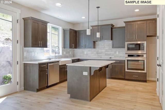 kitchen with a center island, a healthy amount of sunlight, stainless steel appliances, and hanging light fixtures