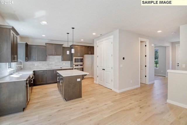 kitchen featuring pendant lighting, light hardwood / wood-style flooring, a kitchen island, and appliances with stainless steel finishes