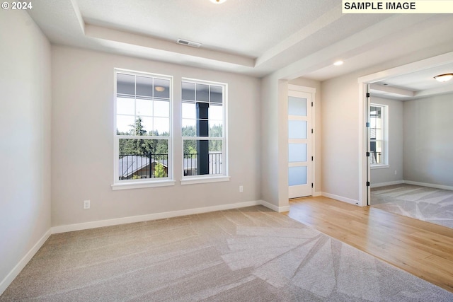 carpeted empty room featuring a tray ceiling