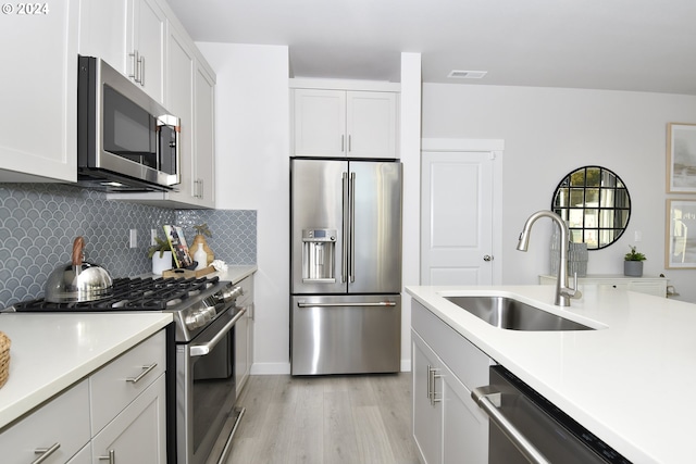 kitchen with sink, decorative backsplash, light hardwood / wood-style floors, white cabinetry, and stainless steel appliances