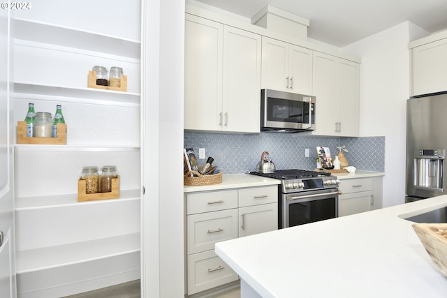 kitchen with white cabinets, wood-type flooring, stainless steel appliances, and tasteful backsplash