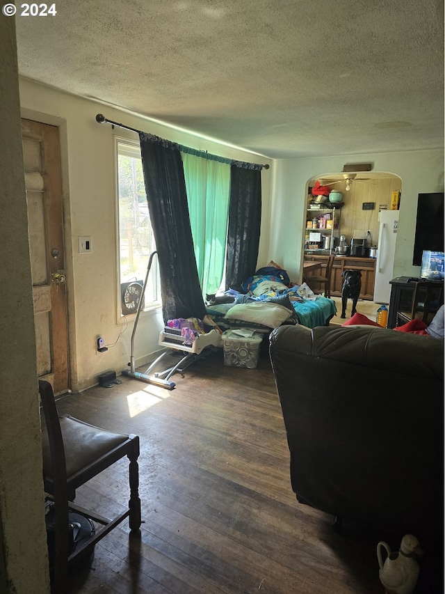 living room with ceiling fan, dark hardwood / wood-style flooring, and a textured ceiling