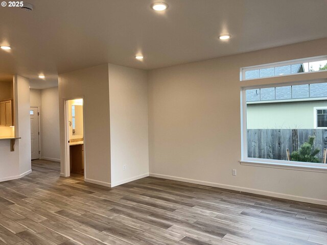 spare room featuring recessed lighting, baseboards, and wood finished floors