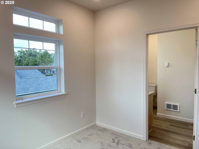 spare room with carpet floors, visible vents, and baseboards