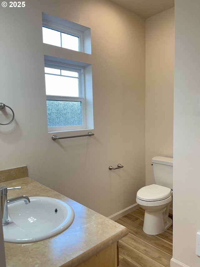 bathroom featuring baseboards, vanity, toilet, and wood finished floors