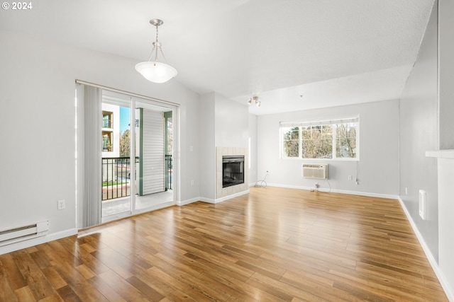 unfurnished living room featuring a tile fireplace, light hardwood / wood-style flooring, a wall mounted AC, and lofted ceiling