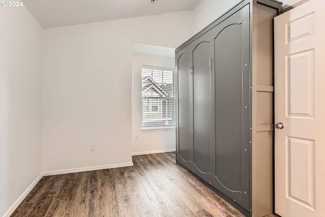 interior space with dark wood-type flooring and vaulted ceiling