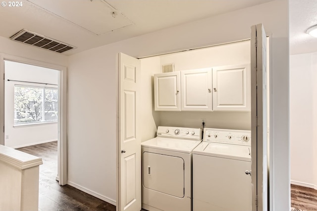 laundry area featuring washing machine and clothes dryer, cabinets, and dark hardwood / wood-style flooring