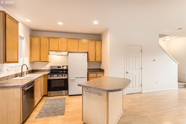 kitchen with stainless steel appliances, sink, a kitchen island, light brown cabinets, and light hardwood / wood-style flooring