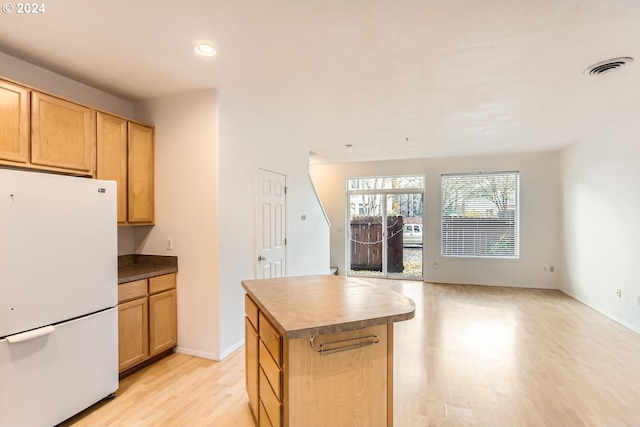 kitchen with light brown cabinets, light hardwood / wood-style floors, a center island, and white refrigerator