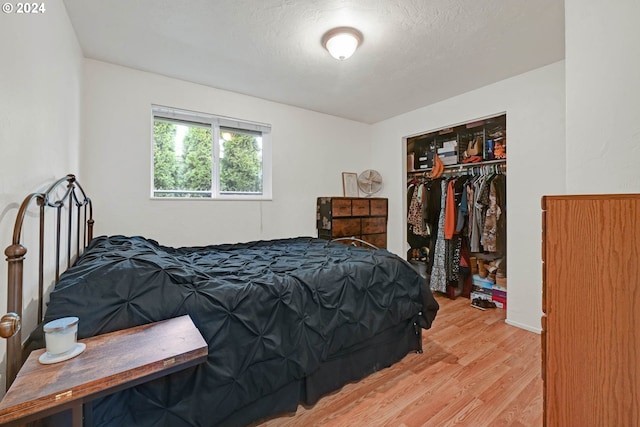 bedroom with light hardwood / wood-style flooring, a textured ceiling, and a closet