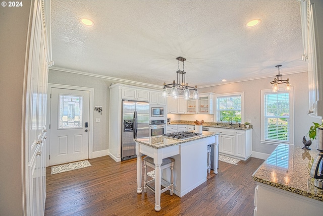 kitchen with stone counters, a center island, appliances with stainless steel finishes, and dark hardwood / wood-style flooring