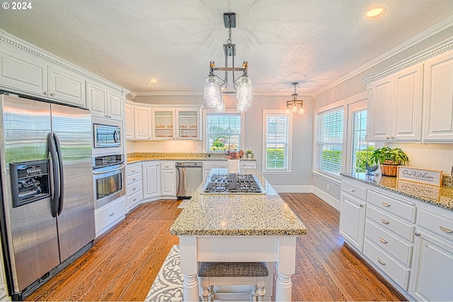 kitchen with built in appliances, crown molding, white cabinetry, and light hardwood / wood-style flooring