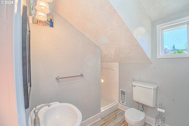 bathroom featuring tiled shower, toilet, a textured ceiling, and vaulted ceiling