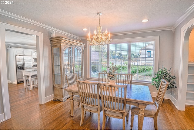 dining area with a textured ceiling, light hardwood / wood-style flooring, ornamental molding, and a chandelier