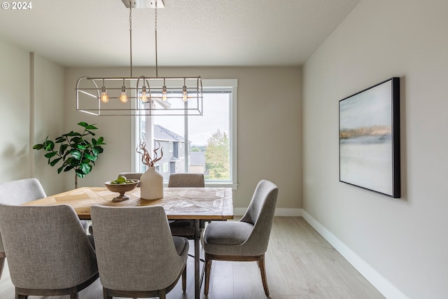 dining room featuring light hardwood / wood-style flooring, a textured ceiling, and an inviting chandelier