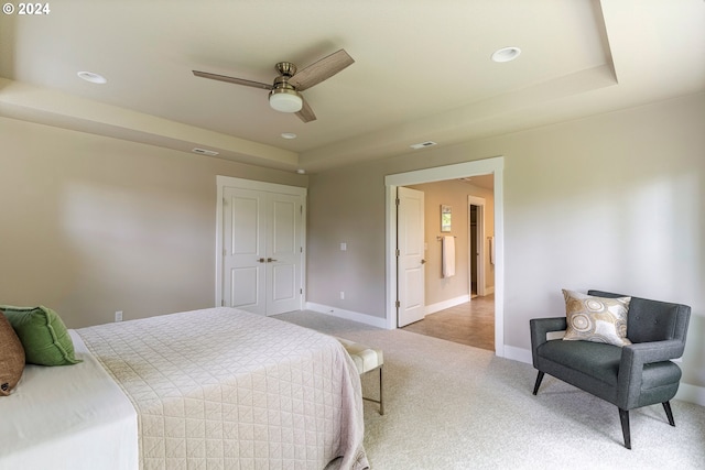 bedroom with light carpet, a raised ceiling, and ceiling fan