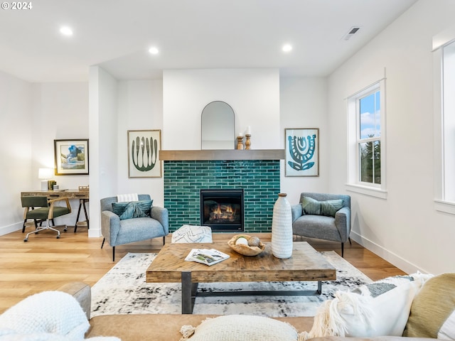 living room with a tile fireplace and light hardwood / wood-style floors