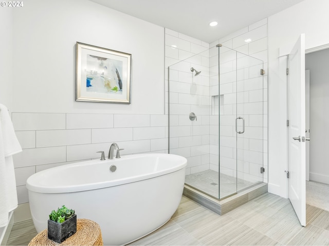 bathroom featuring tile walls and shower with separate bathtub