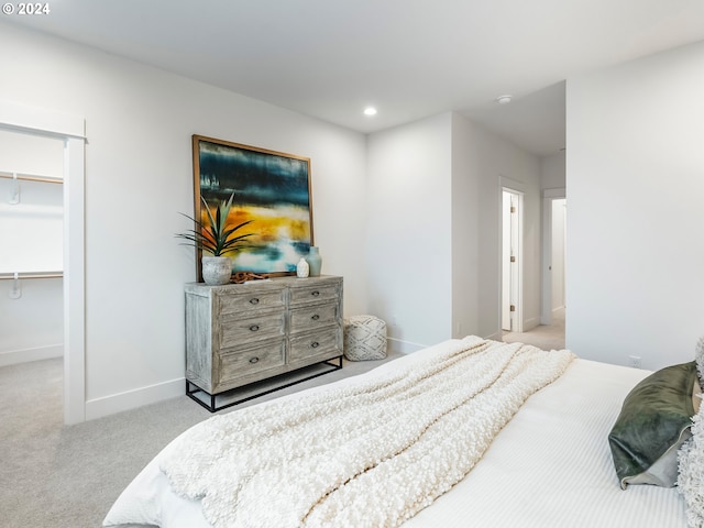 carpeted bedroom featuring a walk in closet and a closet