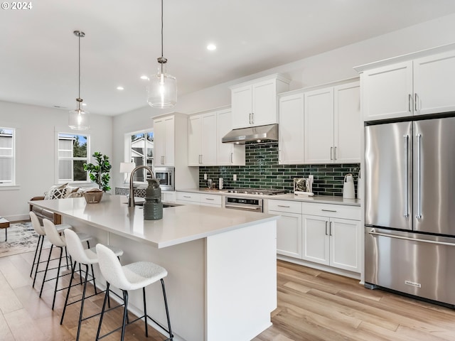 kitchen featuring sink, hanging light fixtures, a center island with sink, white cabinets, and appliances with stainless steel finishes