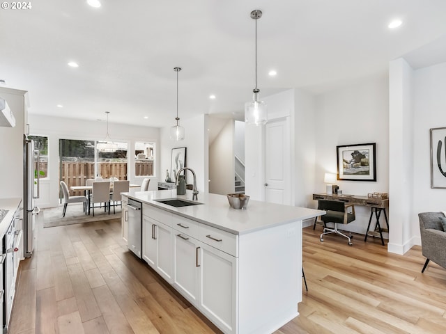 kitchen with white cabinets, sink, an island with sink, and decorative light fixtures