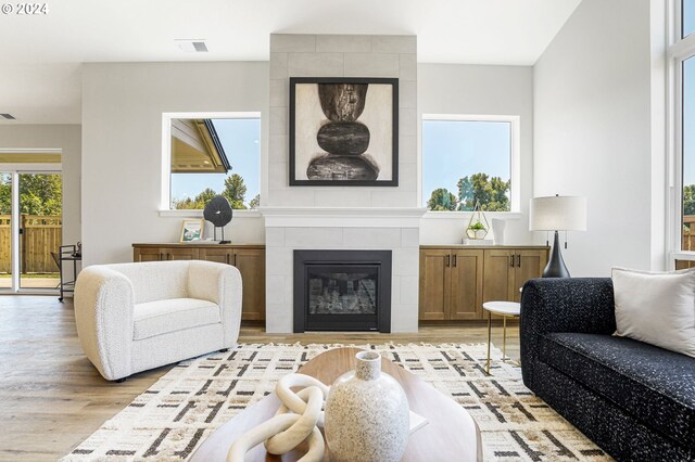 living room with a tile fireplace and light wood-type flooring