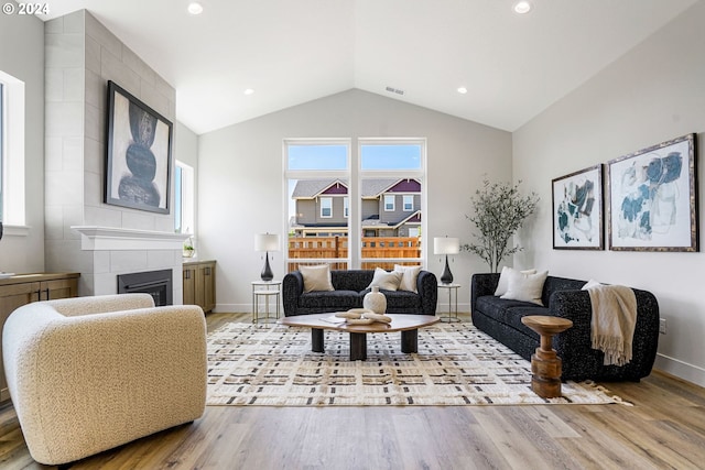 living room featuring a fireplace, light hardwood / wood-style flooring, and vaulted ceiling