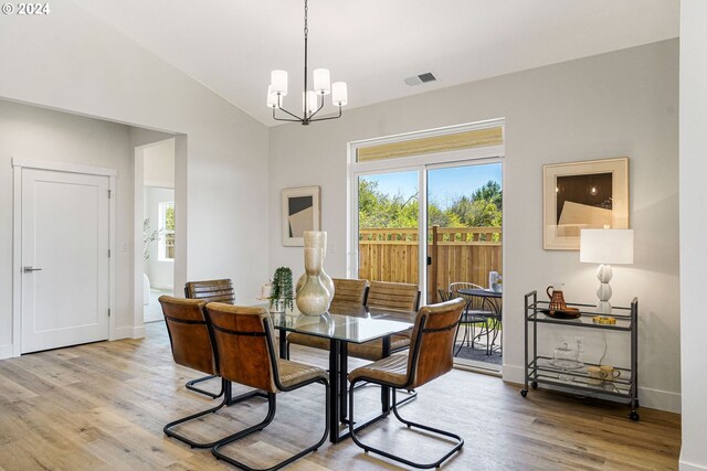 dining room with a chandelier, wood-type flooring, and lofted ceiling