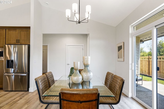 dining space featuring light hardwood / wood-style flooring, vaulted ceiling, and a notable chandelier