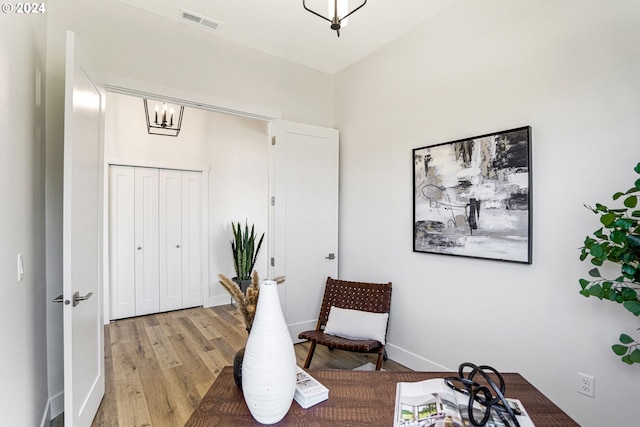 living area with an inviting chandelier and light hardwood / wood-style flooring