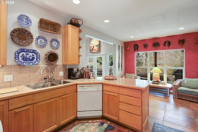 kitchen with french doors, kitchen peninsula, backsplash, dishwasher, and sink