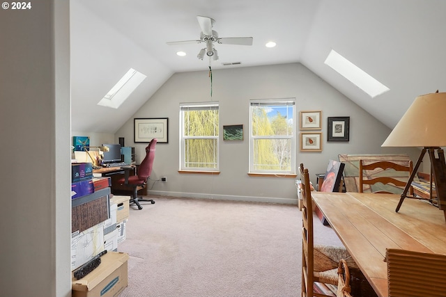 home office with vaulted ceiling with skylight, ceiling fan, and light colored carpet