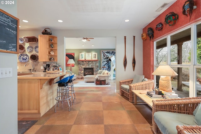 interior space featuring ceiling fan, light tile floors, sink, and a fireplace