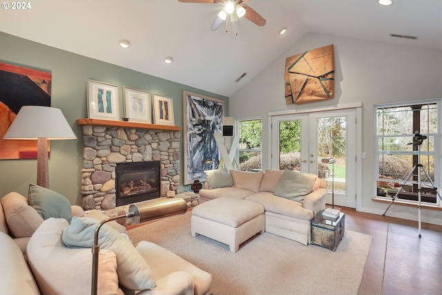 living room featuring high vaulted ceiling, a stone fireplace, french doors, tile flooring, and ceiling fan