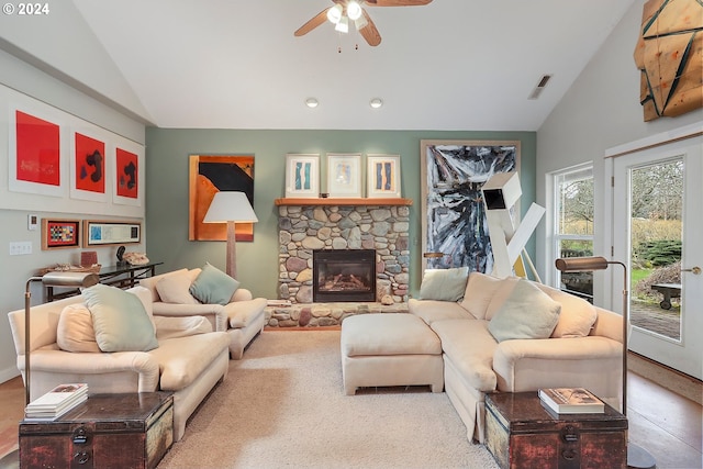 living room featuring a stone fireplace, ceiling fan, and high vaulted ceiling