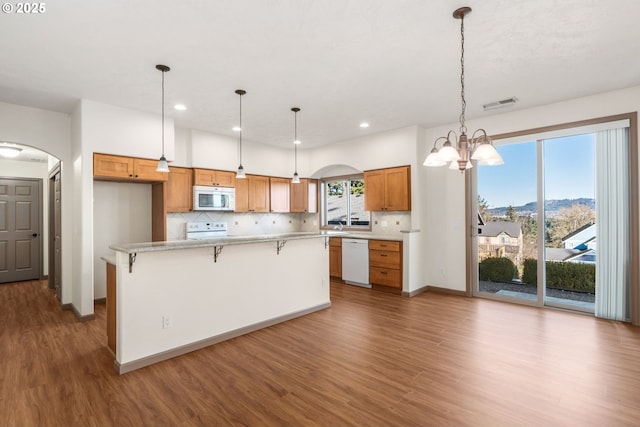 kitchen with white appliances, backsplash, a kitchen breakfast bar, decorative light fixtures, and a chandelier