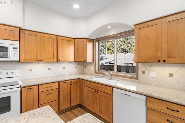 kitchen featuring light stone countertops, white appliances, tasteful backsplash, and sink