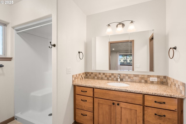 bathroom with decorative backsplash, a shower, and vanity