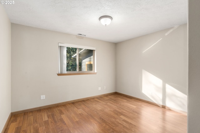 spare room featuring wood-type flooring and a textured ceiling