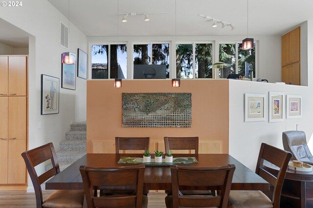 dining room featuring light wood-type flooring, stairway, plenty of natural light, and visible vents