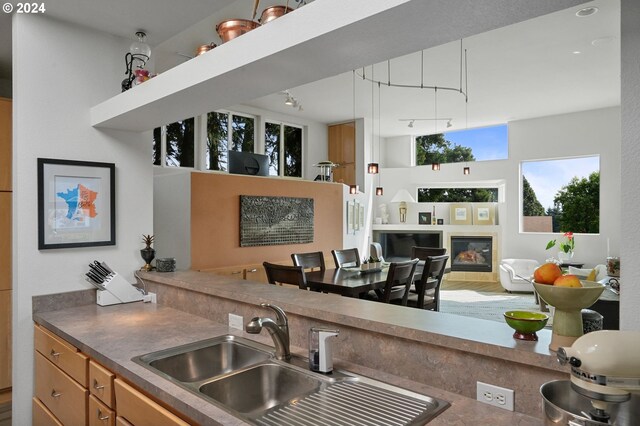 kitchen with dark countertops, a glass covered fireplace, open floor plan, a sink, and track lighting