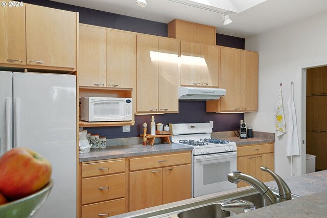 kitchen with light brown cabinets, under cabinet range hood, white appliances, stainless steel countertops, and a skylight