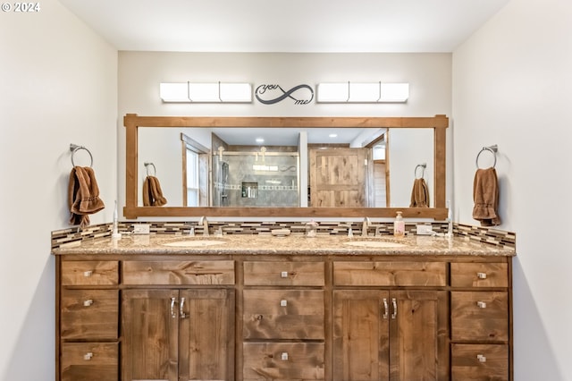 bathroom featuring a shower with shower door and vanity