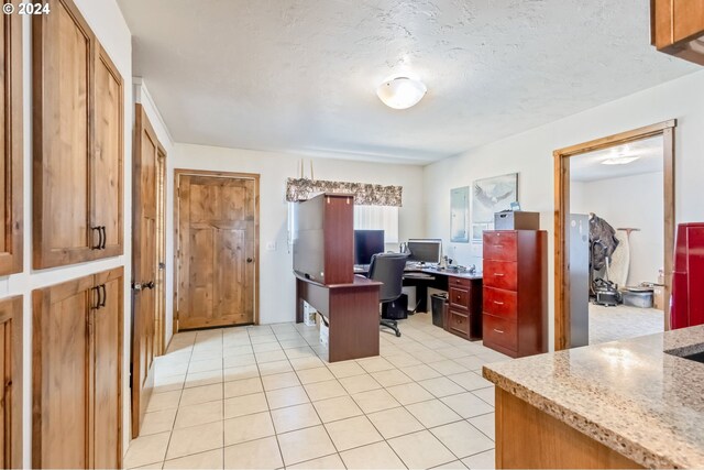 home office with a textured ceiling and light tile patterned flooring