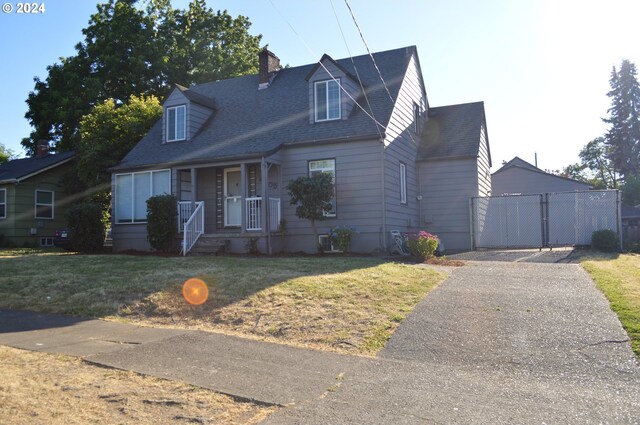 cape cod home featuring a porch and a front lawn