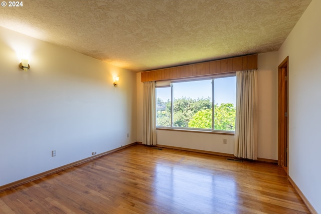 unfurnished room with a textured ceiling and light hardwood / wood-style floors