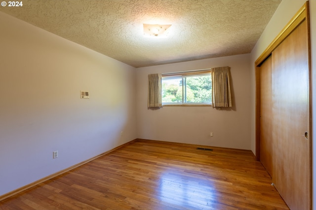 unfurnished bedroom with a closet, a textured ceiling, and hardwood / wood-style floors