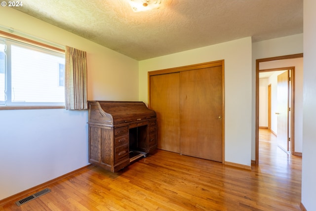 unfurnished bedroom featuring light hardwood / wood-style flooring, a closet, and a textured ceiling