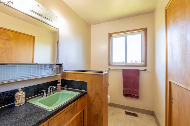 bathroom featuring tile patterned flooring, toilet, and vanity